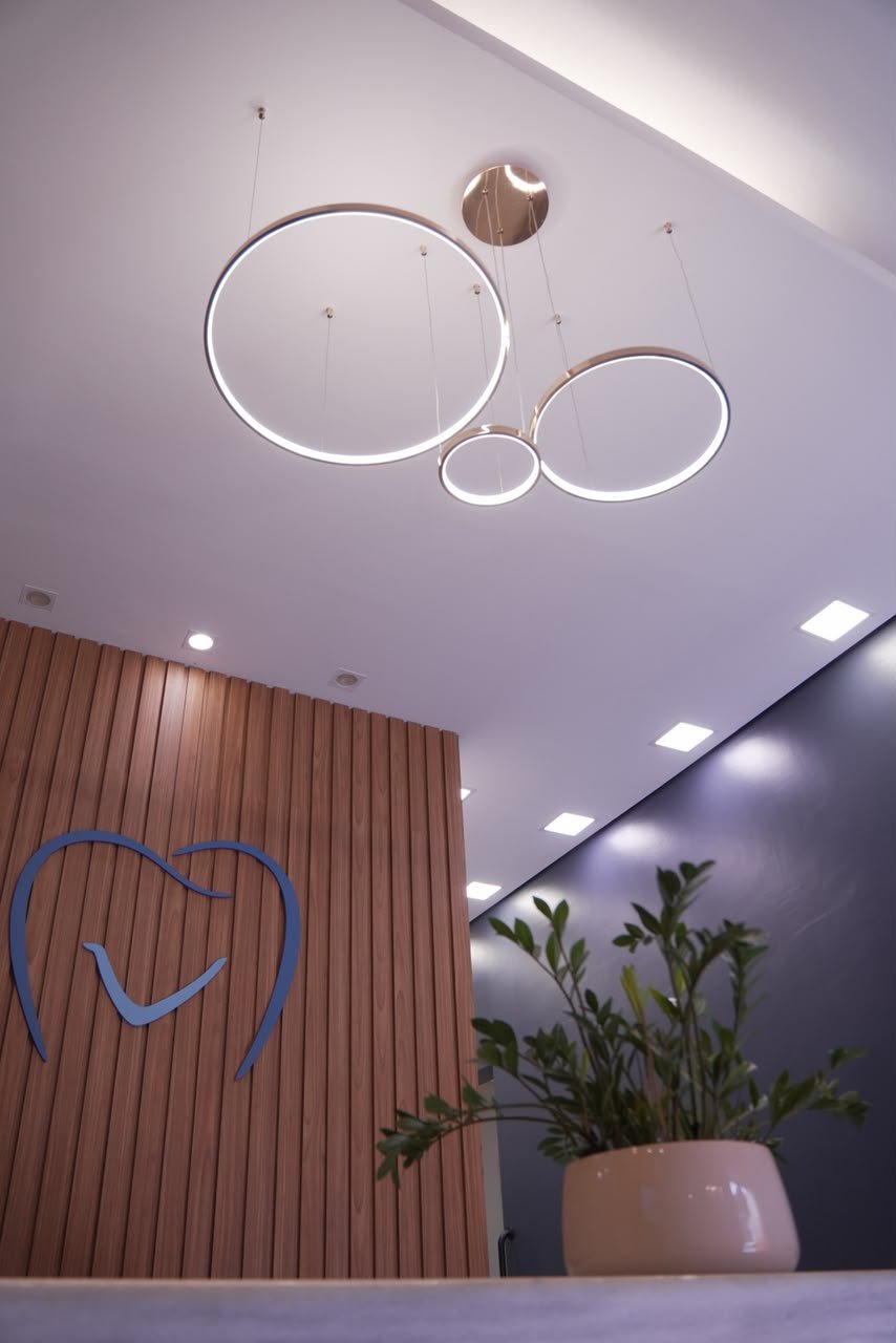 Recepção da VRClinica, com luminárias e o logo na parede de madeira.